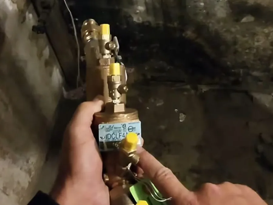 Backflow preventer valve being serviced at an outdoor plumbing connection