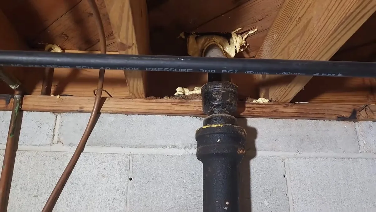 Cast iron drain section near a toilet flange during repair work in an older home