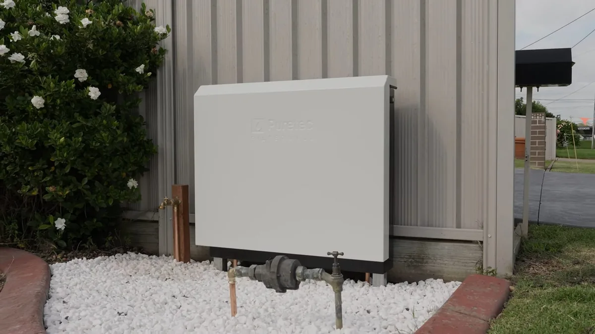 Exterior home filtration box installed near landscaping at an estate property