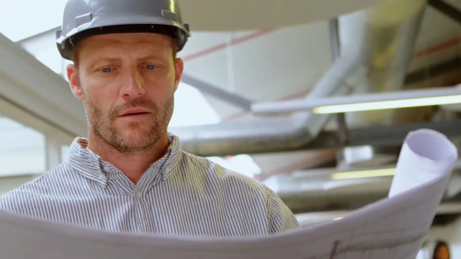 Plumber in a hard hat reviewing pipe plans for an estate project in La Cañada Flintridge