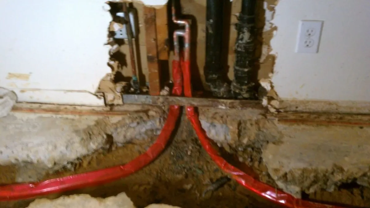 Open wall with red and blue supply lines exposed during residential plumbing repair