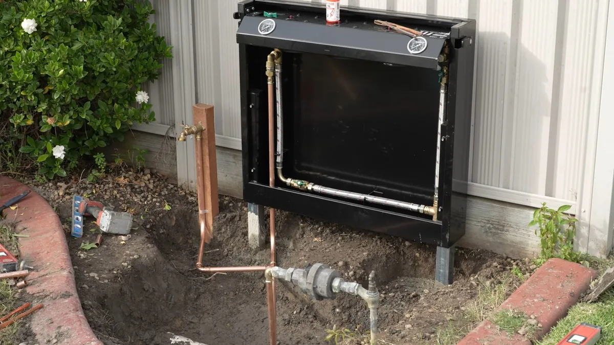 Outdoor filtration equipment beside an estate property plumbing wall