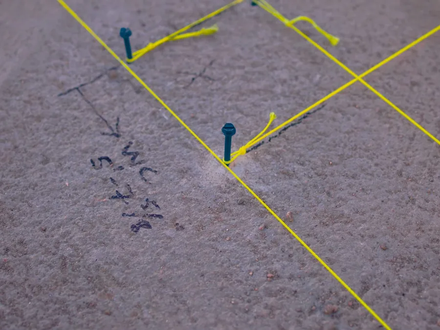 Concrete floor marked with tape to trace a suspected slab leak path