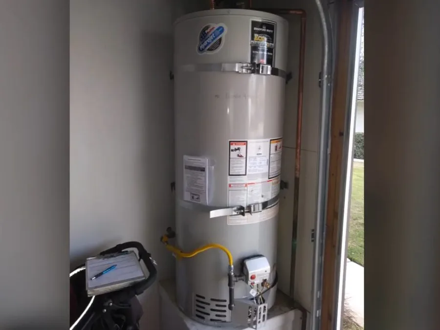 Tank water heater installed in a utility closet with plumbing connections visible