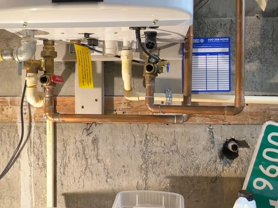 Tankless water heater isolation valves and service connections below the unit