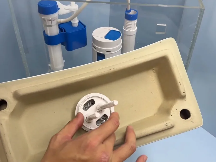 Toilet tank hardware being installed on a removed tank lid area