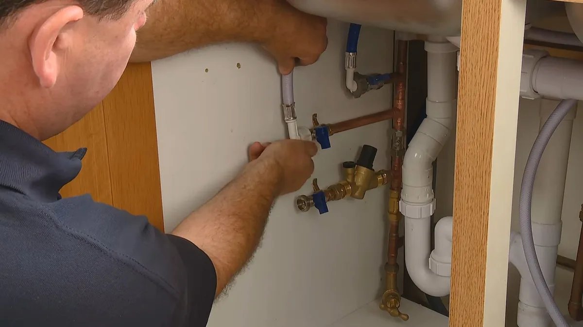 Water softener system installed below a utility area with inlet and outlet connections visible